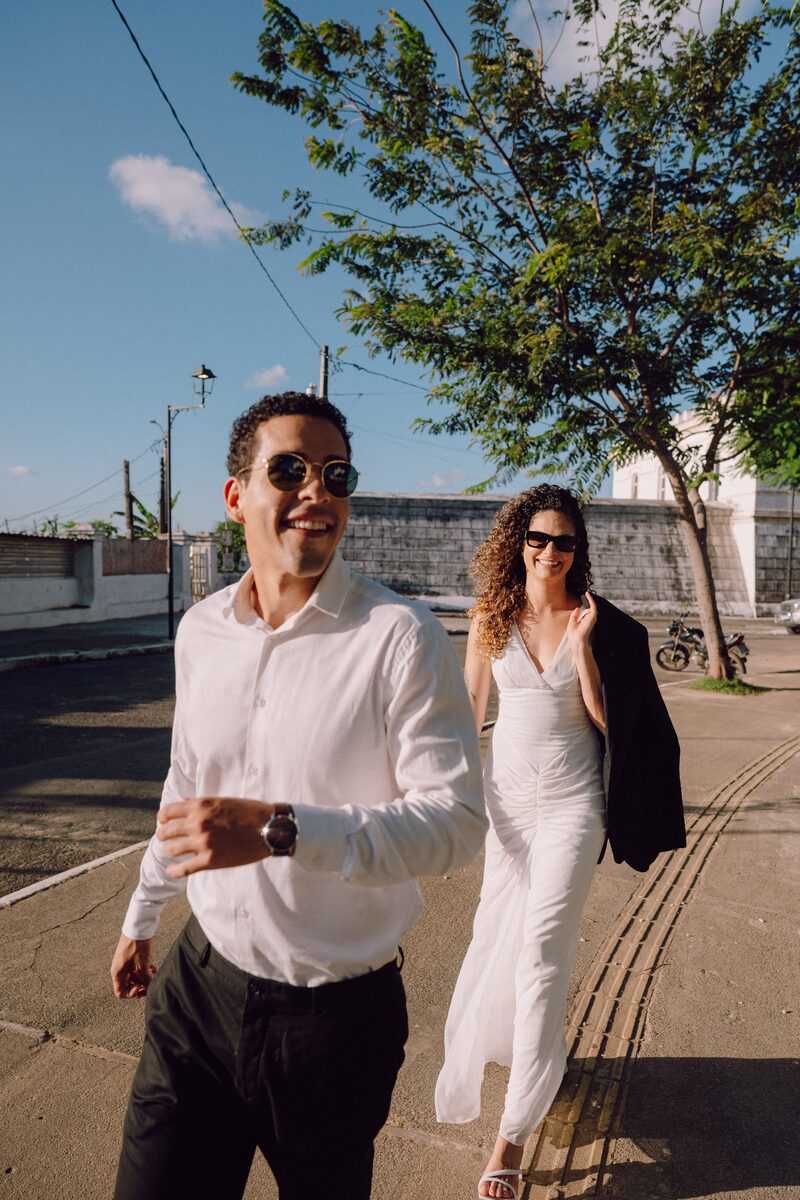 Leo e Tai andando e rindo por uma rua arborizada