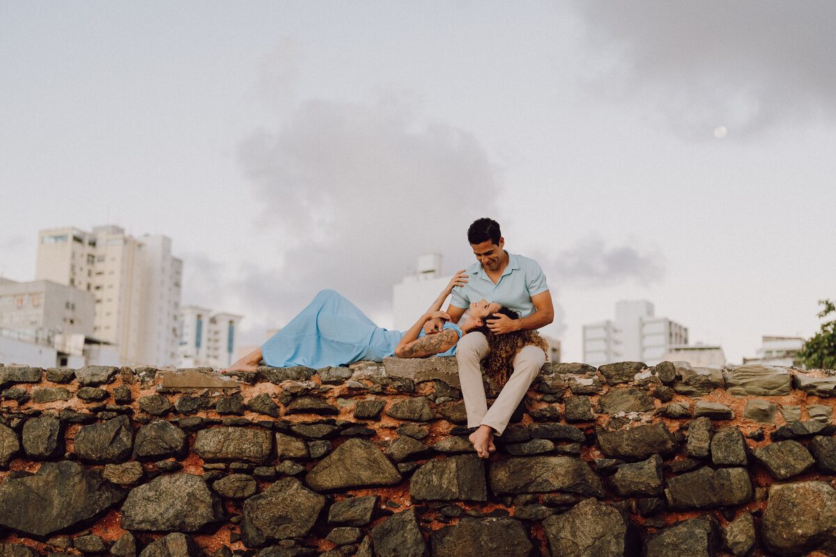 Leo sentado sobre um muro de pedra, olhando para o horizonte de Salvador