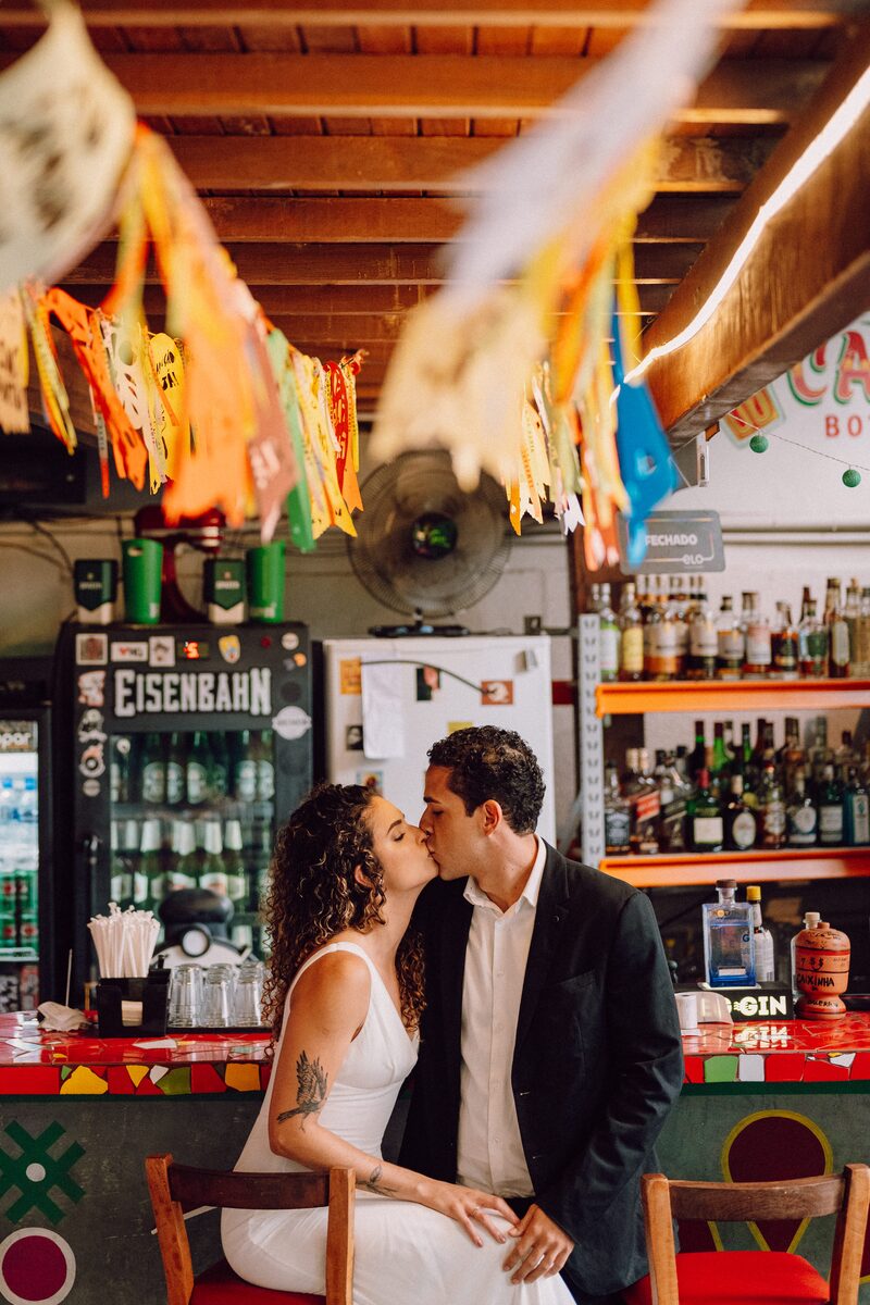 Leo e Tai testa a testa em um bar decorado com bandeirolas
