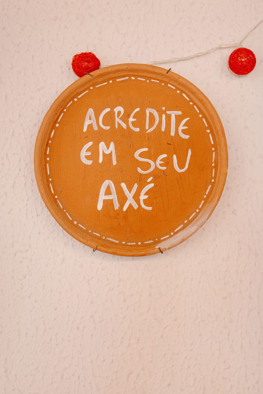 Placa artesanal escrita Acredite em seu Axé pendurada em bar de Salvador