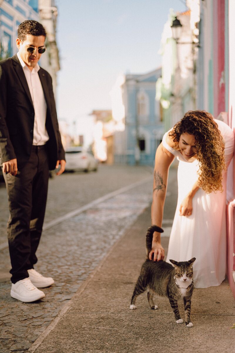 Leo olhando enquanto Tai faz carinho em um gato de rua encontrado durante o ensaio
